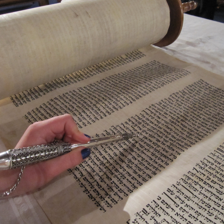 a close up of someone reading the Torah using a yad (pointer)